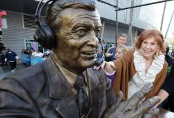Marge Hearn smiles and puts her hand on the shoulder of Chick Hearn's statue.JPG